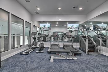 a gym with cardio machines and televisions in a building